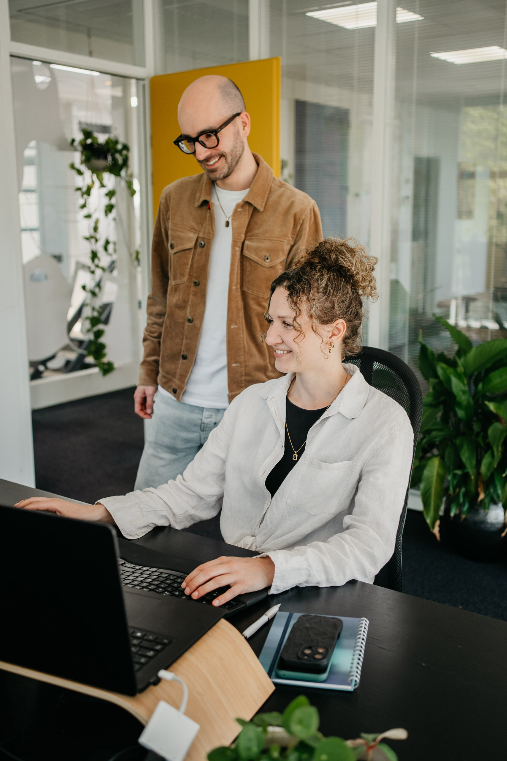 Doordacht: Twee medewerkers kijken samen aan een bureau naar een computerscherm.